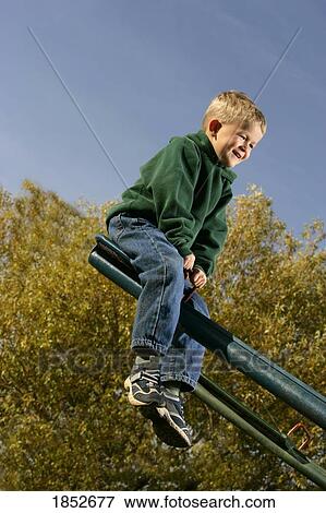 Upward; Boy having fun on a seesaw View Large Photo Image Stock Photo - Upward; Boy having fun on a seesaw. Fotosearch