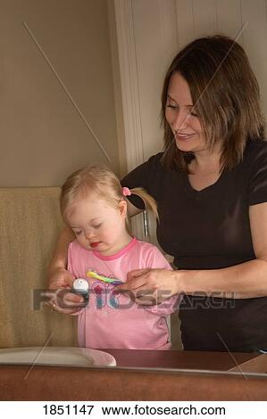 Stock Photo - Woman and girl; Mother brushing daughter's teeth. Fotosearch