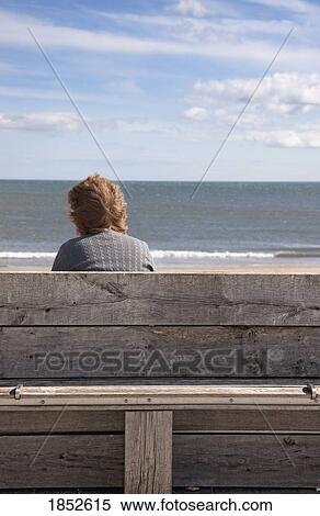 Stock Photography - Woman and water; Woman sitting on a bench looking at a body of water. Fotosearch