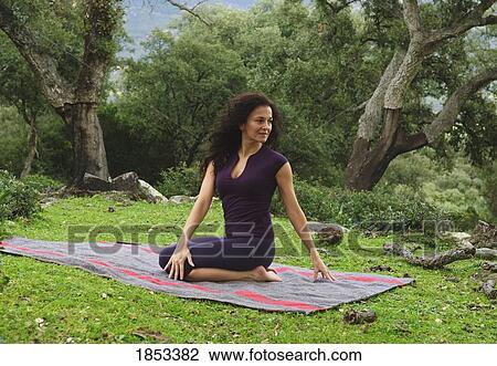 Stock Image - Woman in position on yoga mat outdoors. Fotosearch