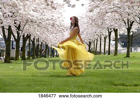 Woman in yellow dress dancing among flowering trees View Large Photo Image Stock Photo - Woman in yellow dress dancing among flowering trees. Fotosearch