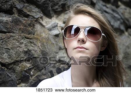 woman with sunglasses; woman with sunglasses standing next to a stone wall View Large Photo Image Stock Image - woman with sunglasses; woman with sunglasses standing next to a stone wall. Fotosearch