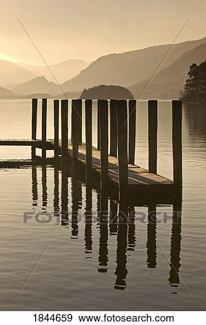 Stock Photo - Wooden dock in the lake at sunset, Cumbria, England. Fotosearch