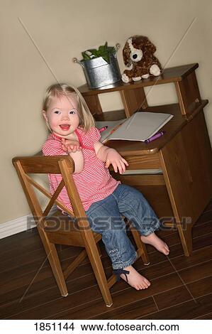 Picture - Young girl sitting at her desk. Fotosearch