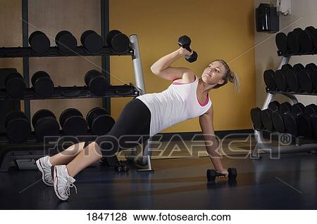 Stock Photo - Young woman using weights. Fotosearch