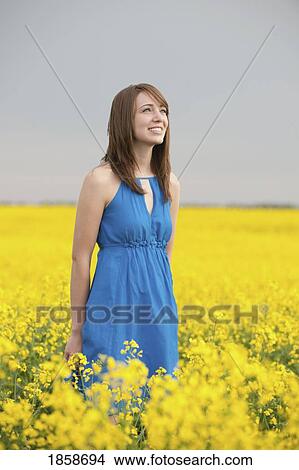 Picture - A young woman in a canola field. Fotosearch