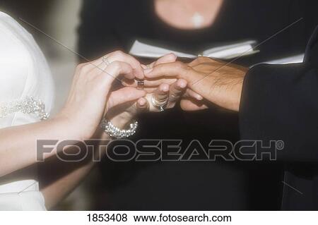 Stock Photo - Bride and groom exchanging rings. Fotosearch