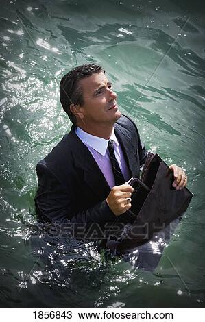 Stock Image - Businessman walking in deep water. Fotosearch