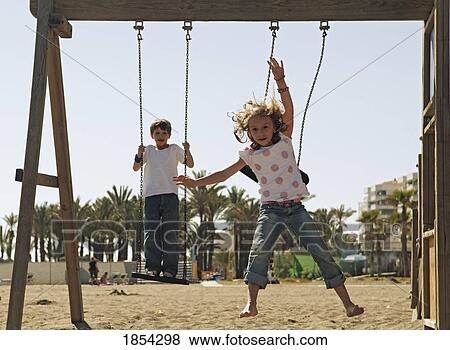 Stock Photo - Children playing on swing set. Fotosearch