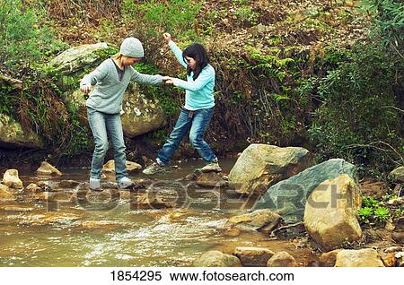 Children walking on stones across water View Large Photo Image Stock Photography - Children walking on stones across water. Fotosearch