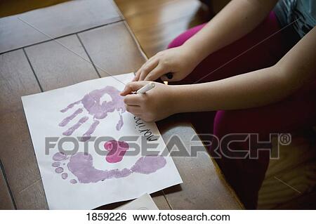 Stock Photograph - Girl making hand and footprints on paper. Fotosearch