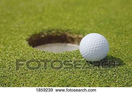Stock Photo - Golf ball near a hole. Fotosearch
