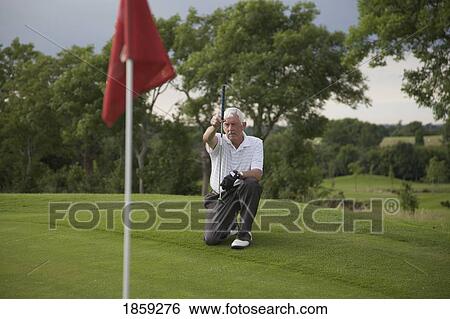 Stock Photograph - Golfer measuring hole. Fotosearch