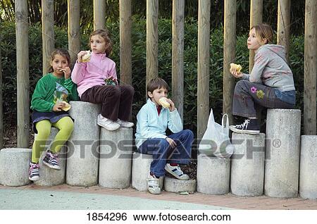 Stock Photograph - Kids sitting outside, eating. Fotosearch