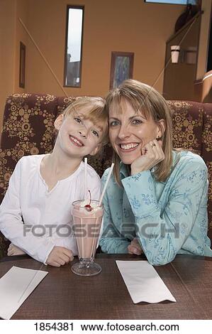Mother and daughter sharing a strawberry milkshake View Large Photo Image Stock Image - Mother and daughter sharing a strawberry milkshake. Fotosearch
