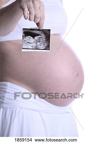 Picture - Pregnant lady holding ultrasound picture. Fotosearch
