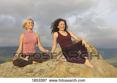 Two women sitting on a boulder View Large Photo Image Stock Photo - Two women sitting on a boulder. Fotosearch