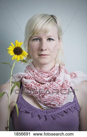 Stock Image - Woman holding a daisy with missing petals. Fotosearch