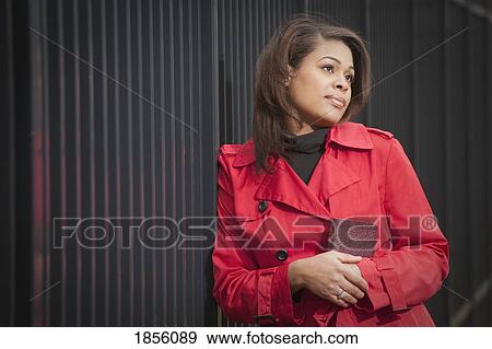 Woman in red coat, holding a book View Large Photo Image Stock Photo - Woman in red coat, holding a book. Fotosearch
