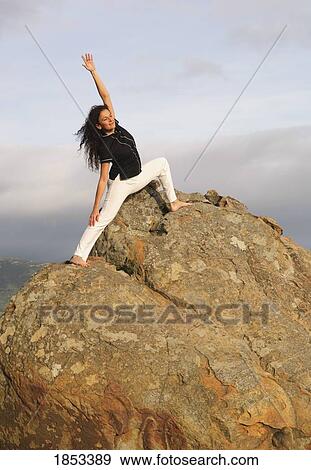 Stock Photo - Woman in yoga position on large boulder. Fotosearch