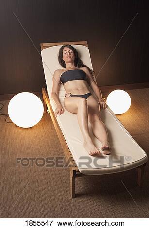 Woman lounging on a chair in her bathing suit View Large Photo Image Stock Photo - Woman lounging on a chair in her bathing suit. Fotosearch