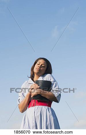 Stock Image - Woman outside with Bible praying. Fotosearch