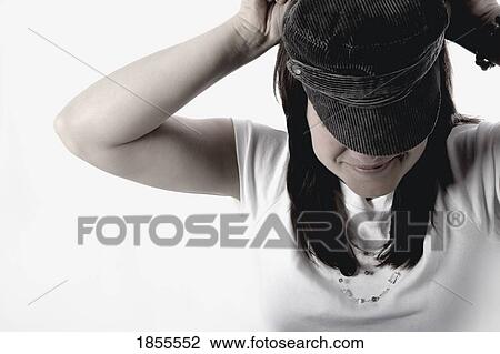 Stock Image - Woman putting on a hat. Fotosearch