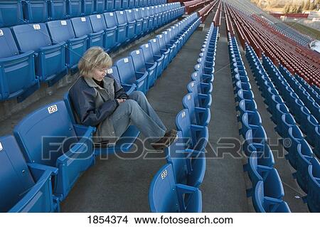 Woman sitting alone in stadium View Large Photo Image Picture - Woman sitting alone in stadium. Fotosearch