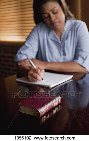 Woman sitting with Bible taking notes View Large Photo Image Stock Image - Woman sitting with Bible taking notes. Fotosearch