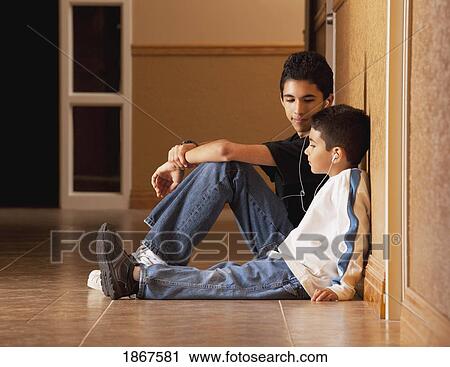 Brothers sitting on the floor listening to music View Large Photo Image Stock Image - Brothers sitting on the floor listening to music. Fotosearch