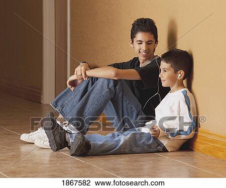 Brothers sitting on the floor listening to music View Large Photo Image Stock Image - Brothers sitting on the floor listening to music. Fotosearch