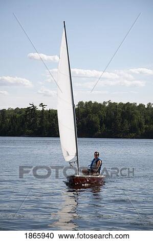 Stock Image - Person in sailboat, Lake of the Woods, Ontario, Canada. Fotosearch