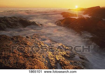 Stock Image - Setting sun over tide-washed rocks, Pacific Rim National Park, Vancouver Island, British Columbia, Canada. Fotosearch