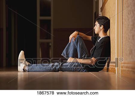 Stock Photo - Teenage boy sitting on the floor listening to music. Fotosearch