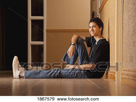 Teenage boy sitting on the floor listening to music View Large Photo Image Stock Photo - Teenage boy sitting on the floor listening to music. Fotosearch