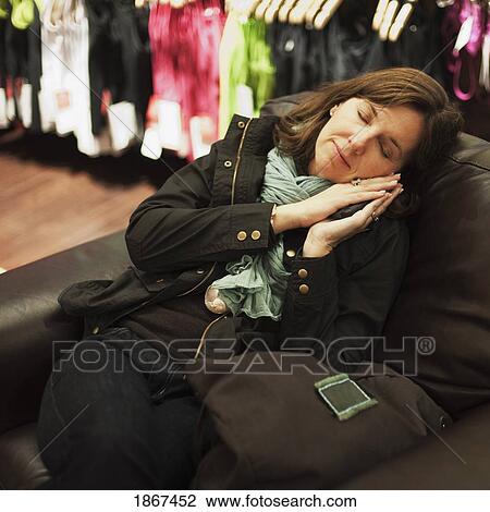 Stock Image - Woman resting on a chair in a clothing store. Fotosearch