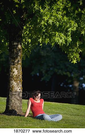 a girl relaxing on the grass under a tree View Large Photo Image Stock Photo - a girl relaxing on the grass under a tree. Fotosearch