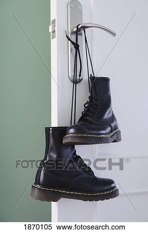 A pair of black boots tied together by the laces and hanging from a doorknob Stock Photography