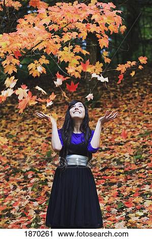 Stock Image - a teenage girl playing with the leaves in autumn. Fotosearch