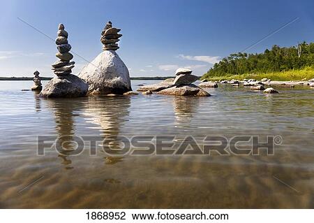 Stock Image - alberta, canada; rocks piled in the shallow water along the shore. Fotosearch