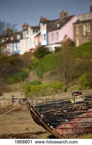 Stock Image - alnmouth, northumberland, england; the bow of a worn boat tied up with houses in the background. Fotosearch