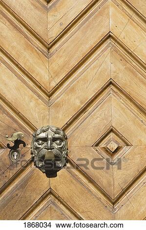 Picture - brass door handle on a wooden door, bolzano, alto adige, italy. Fotosearch