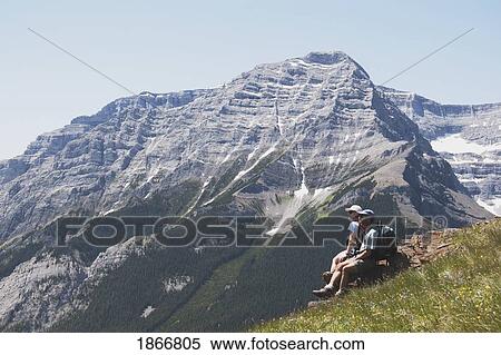 Stock Photography - Couple sitting on the top of a mountain. Fotosearch