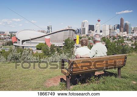 Elderly couple sitting on a bench overlooking the Saddledome, Calgary, Alberta, Canada View Large Photo Image Stock Photo - Elderly couple sitting on a bench overlooking the Saddledome, Calgary, Alberta, Canada. Fotosearch
