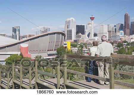 Stock Image - Elderly couple standing, overlooking the Saddledome, Calgary, Alberta, Canada. Fotosearch