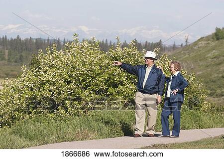 Stock Photograph - Elderly couple walking on a path and pointing. Fotosearch