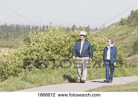 Stock Image - Elderly couple walking on a path. Fotosearch