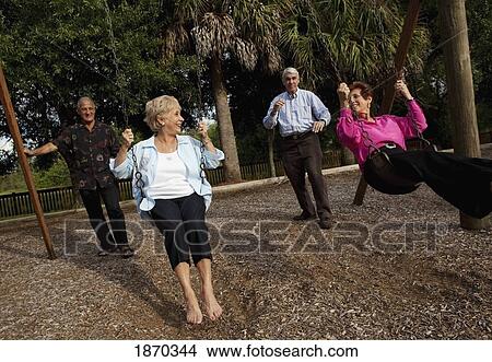 fort lauderdale, florida, united states of america; two married couples with the men pushing the women on the swings View Large Photo Image Picture - fort lauderdale, florida, united states of america; two married couples with the men pushing the women on the swings. Fotosearch