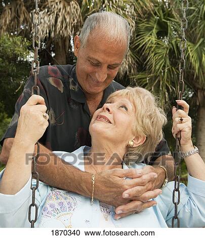 Stock Image - fort lauderdale, florida, united states of america; a couple with the woman sitting on a swing. Fotosearch