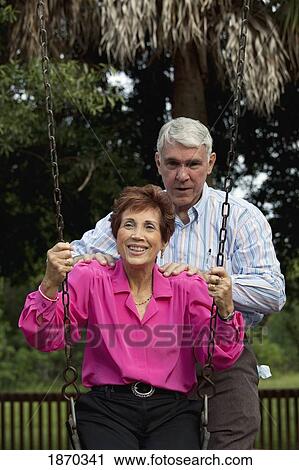 Stock Image - fort lauderdale, florida, united states of america; a couple with the woman sitting on a swing. Fotosearch